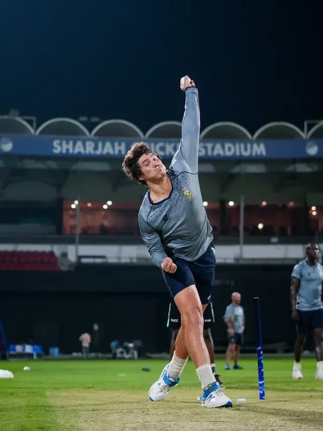 Young bowler mid-delivery at Sharjah Cricket Stadium during a tour fixture
