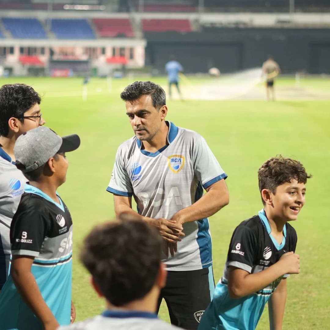 Coach guiding a young player through a cricket drill