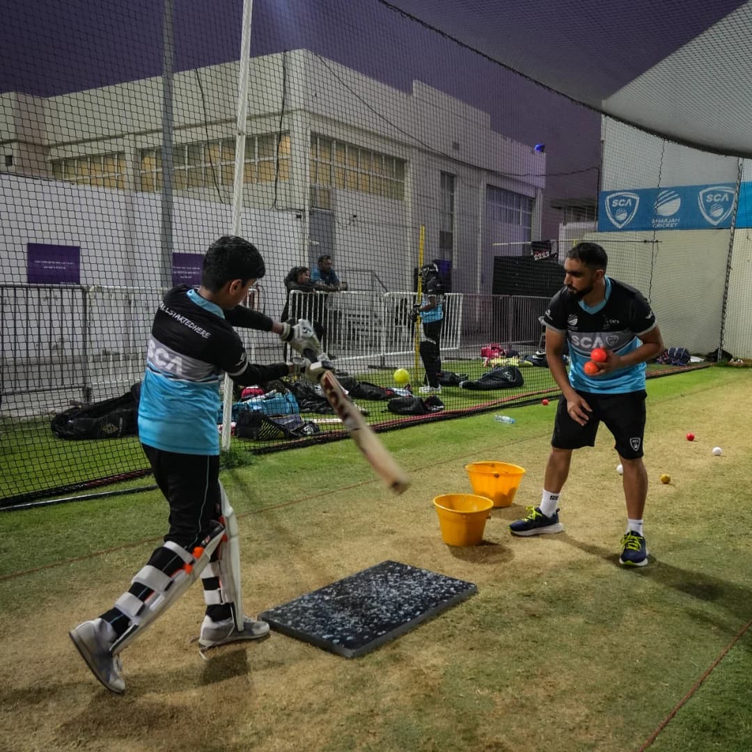 Coach delivering throwdowns to a batter in the practice nets