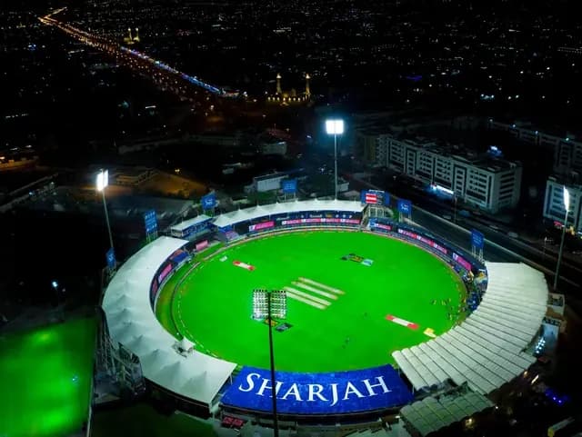 Aerial night view of Sharjah Cricket Stadium, illuminated for a match